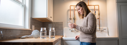 Homeowner comparing water samples near exposed household plumbing