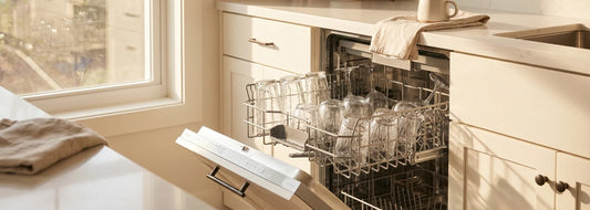 Open dishwasher with rack of glasses showing cloudy white film from hard water