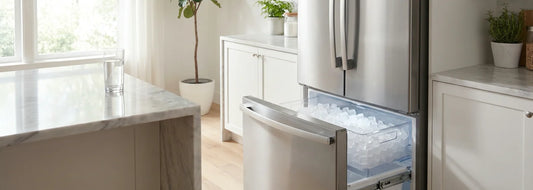Stainless steel French-door refrigerator with the freezer drawer open showing ice maker bin
