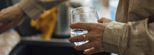 Person holding a glass of tap water near a kitchen sink