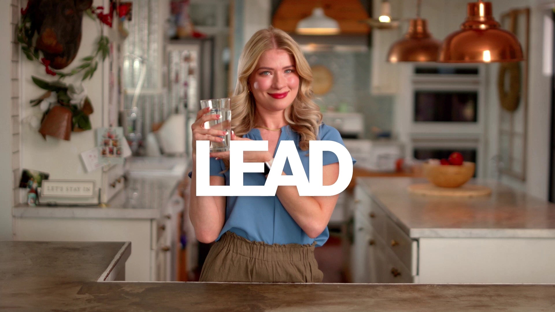 Woman holding a glass of water in a kitchen with 'LEAD' text overlay