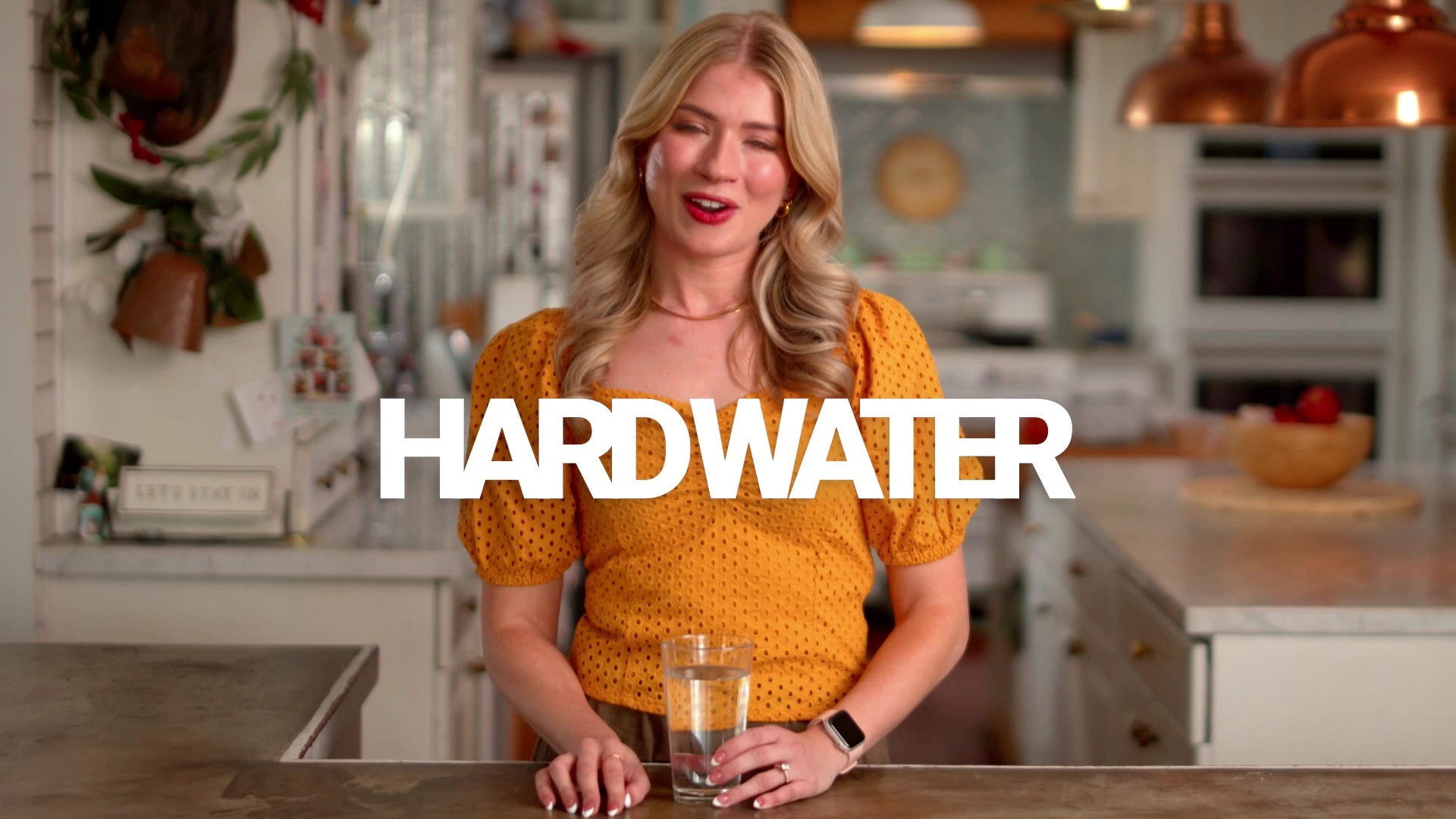 Woman holding a glass of water in a kitchen with 'Hardwater' text overlay