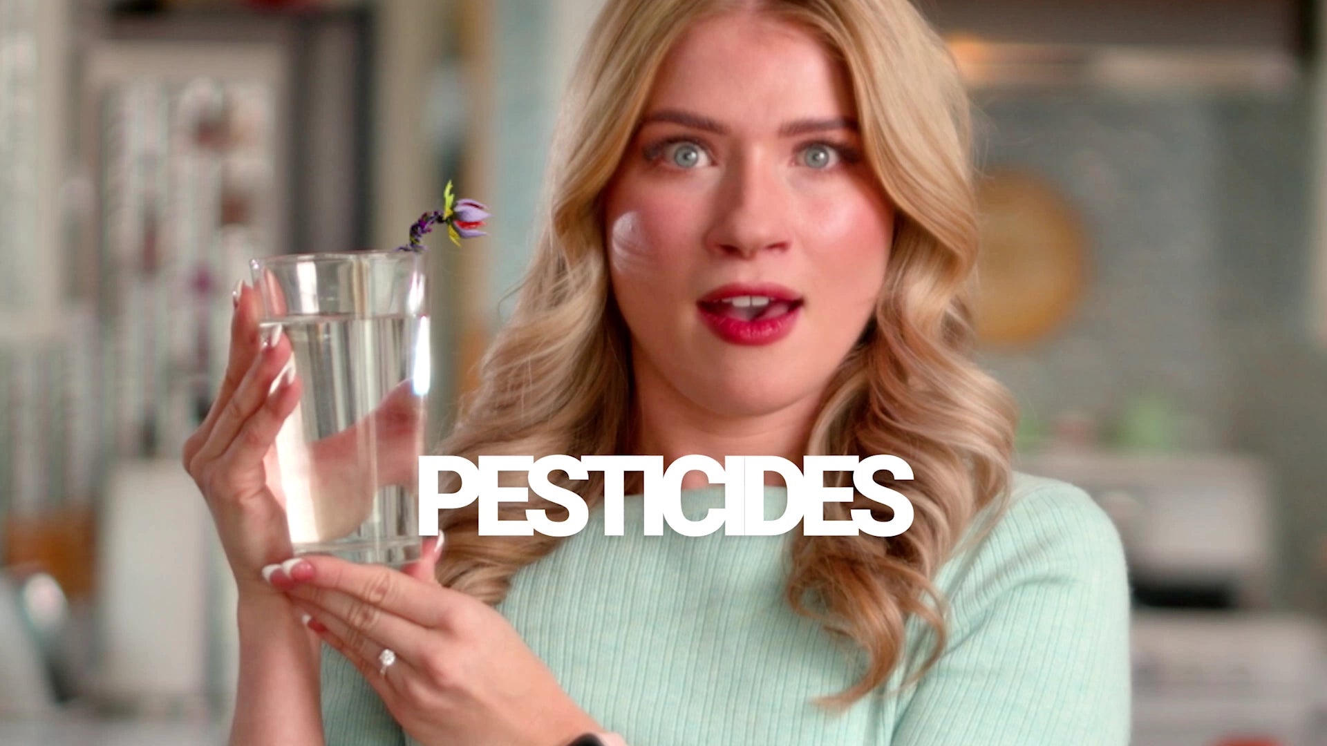 Woman holding a glass of water with a flower, with the word 'PESTICIDES' displayed.